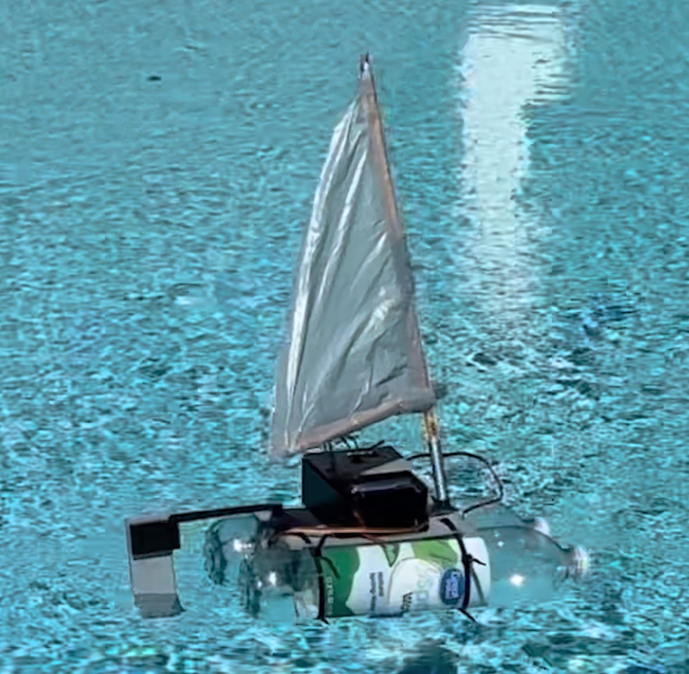 The remote-control catamaran sailboat sailing on a pool
